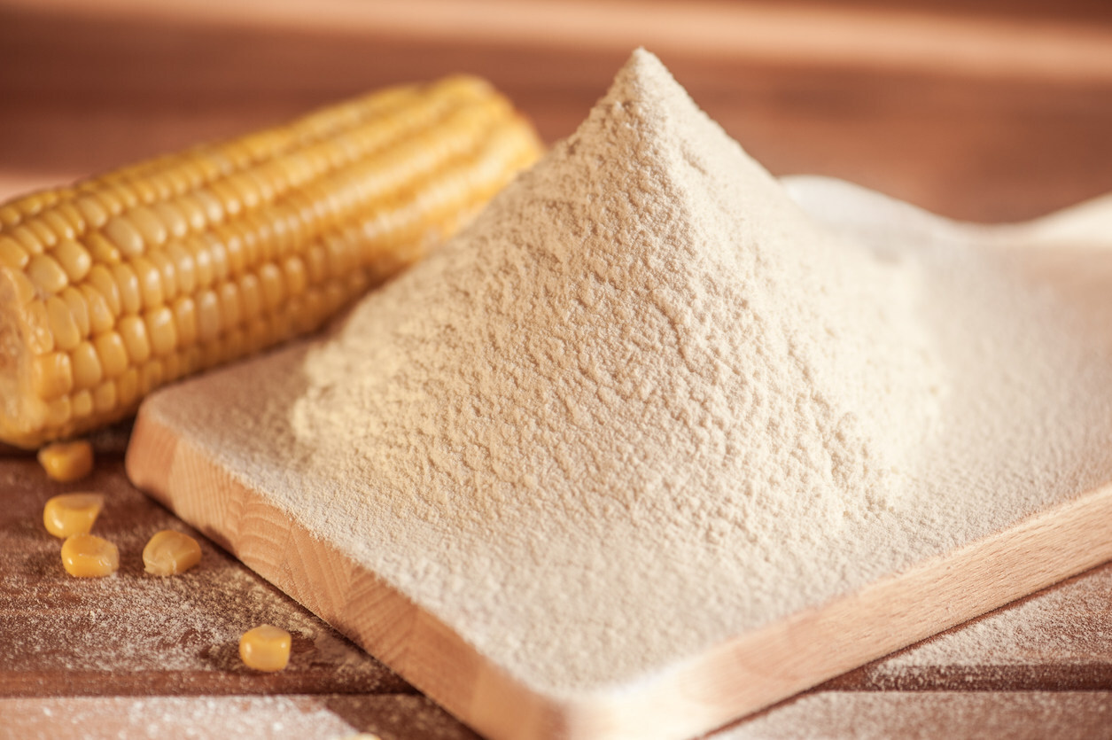 Corn flour and corn on the cob on a wooden table.